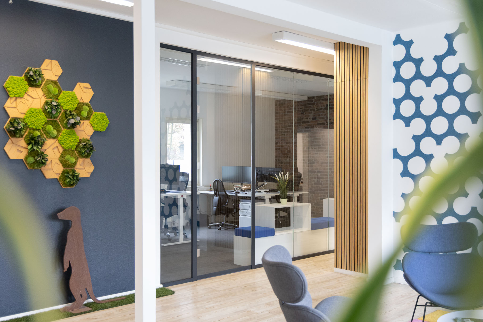 Büro mit Glaswand, Hexagon-Mooswand und Erdmann-Erdmännchen aus Cortenstahl