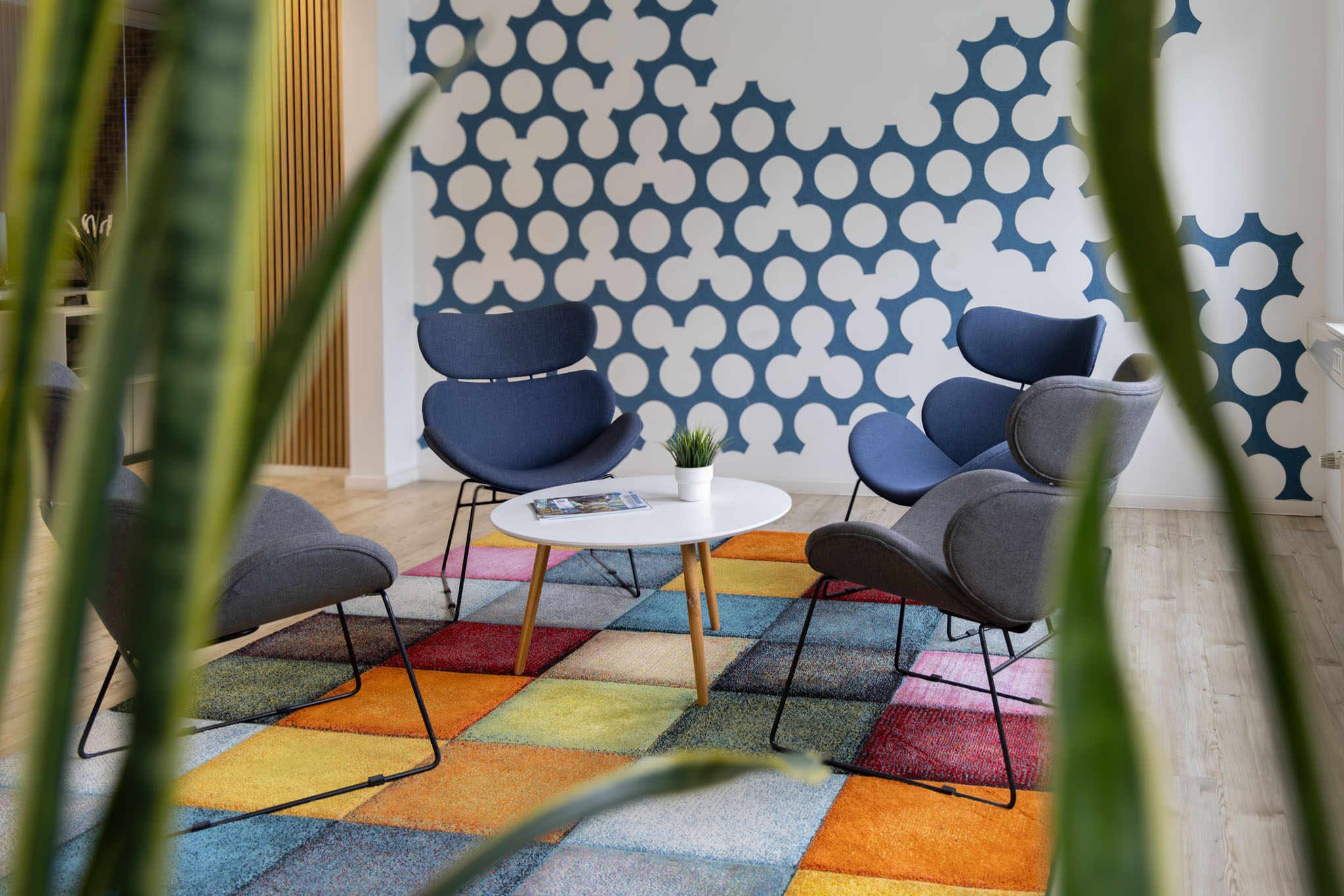 Lounge-Ecke mit Design-Sesseln und buntem Teppich